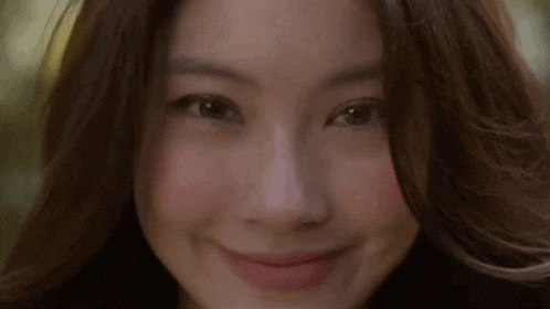 a close up of a woman 's face with long hair smiling .