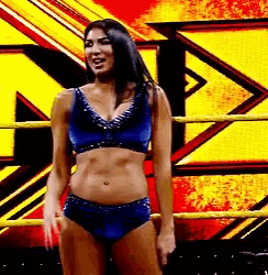 a woman is standing in a wrestling ring wearing a blue bikini top and shorts .