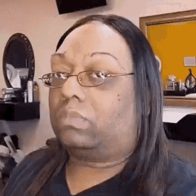a woman with long hair and glasses is making a funny face in front of a mirror .