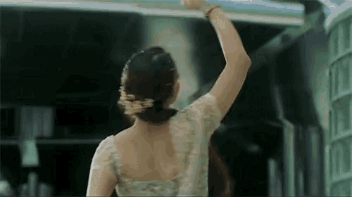 a woman in a white lace top holds her arm up