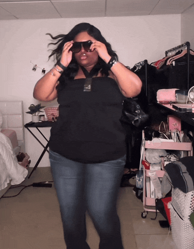 a woman wearing sunglasses is standing in a room with a pink cart