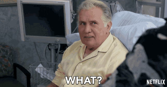 an elderly man in a hospital bed says " what "