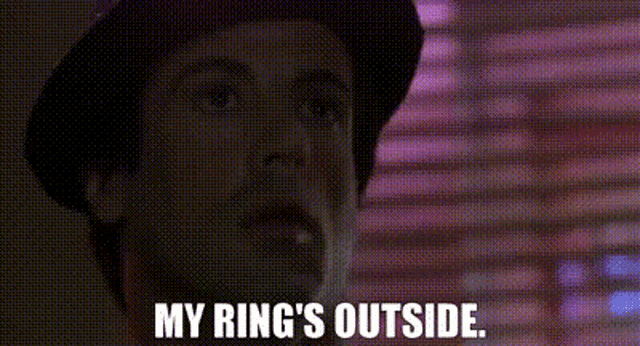 a man in a hat is standing in front of a window and says `` my ring 's outside '' .