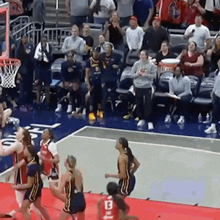 a group of female basketball players are playing a game on a court .