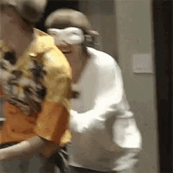 a group of people are standing next to each other in a room and one of them is wearing a mask .