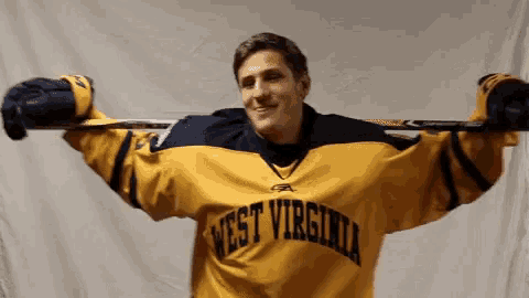 a man in a west virginia jersey is holding a hockey stick