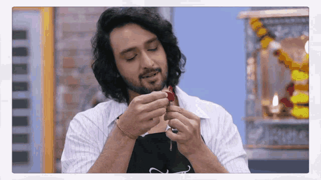 a man with long hair and a beard is holding something in his hands .