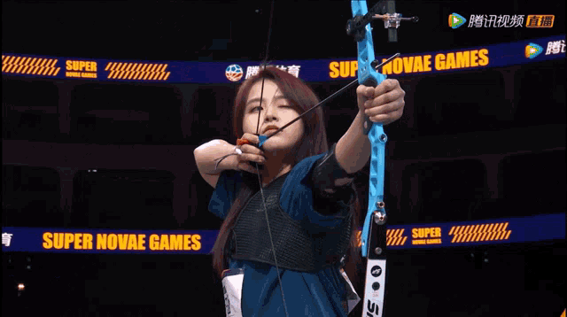a woman is holding a bow and arrow in front of a super banner