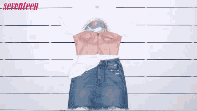 a woman is holding a denim skirt and a white t-shirt with seventeen written on it