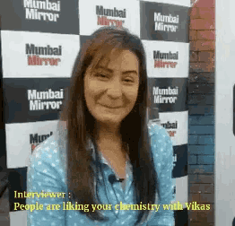 a woman smiles in front of a mumbai mirror banner