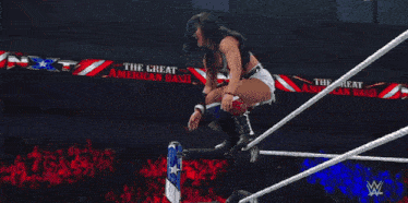 a man is laying on a table in a wrestling ring with a crowd watching .