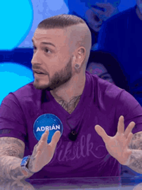 a man in a purple shirt has a name tag that says adrian on it