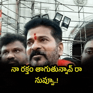 a man with a red dot on his forehead is surrounded by other men and the caption reads " mango "