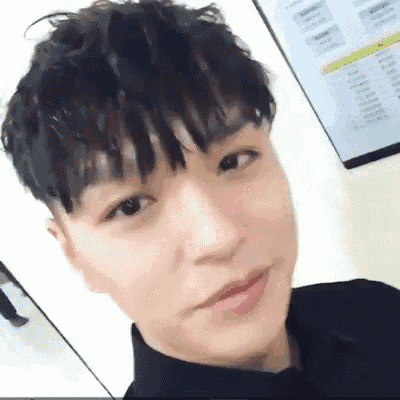 a close up of a young man 's face with a fringe and a black shirt .