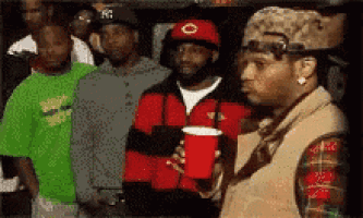 a man is holding a red cup in front of a crowd of people
