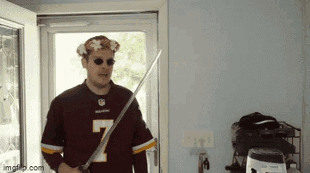 a man wearing a redskins jersey holds a sword