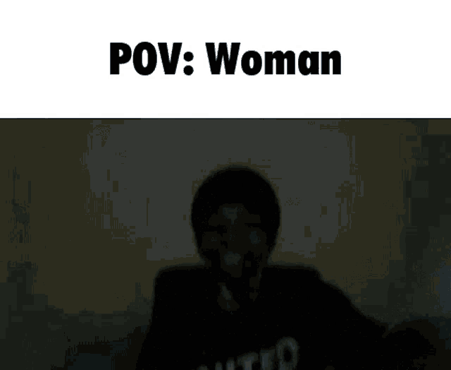 a person in a united sweatshirt is holding a white object in a dark room .