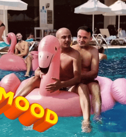 two men sitting on a pink flamingo float in a pool
