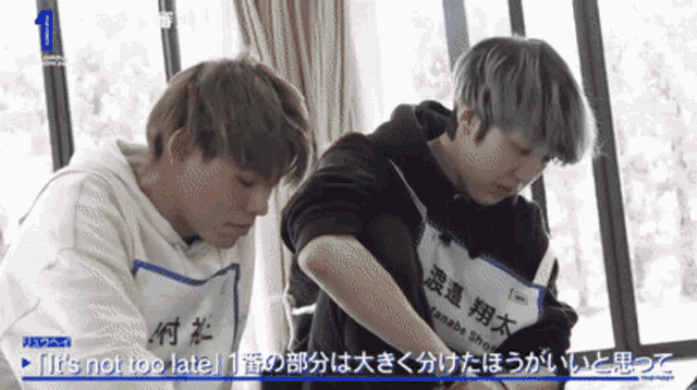 two boys are sitting next to each other and one of them has a name tag that says it 's not too late