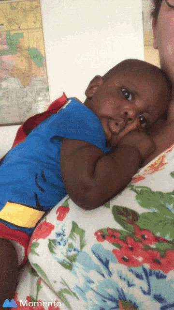 a baby in a superman costume is being held by a woman in a momento photo