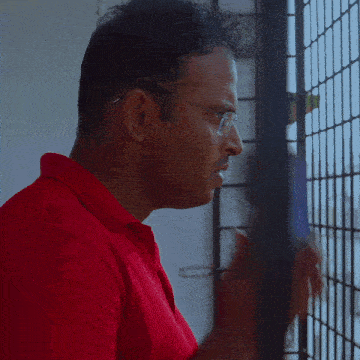 a man in a red shirt is talking on his phone