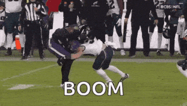 a football player is being tackled by another player on a field while a referee watches .