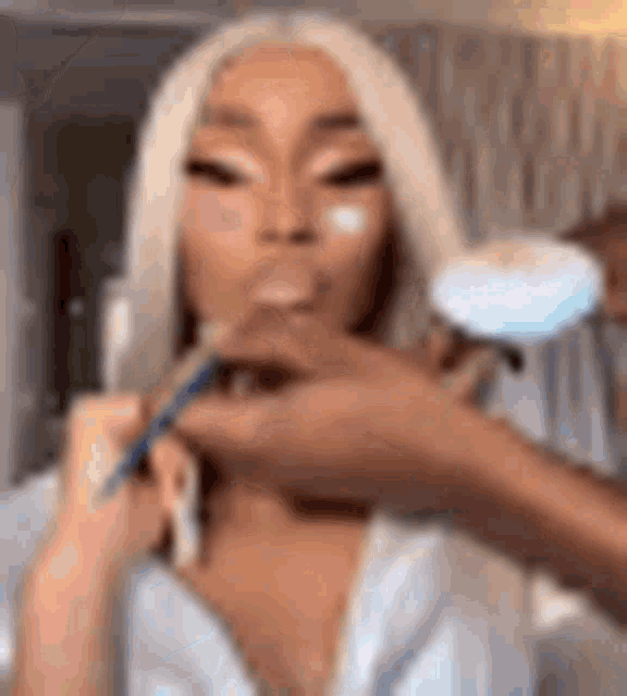 a woman is getting her makeup done by a man in a white robe .