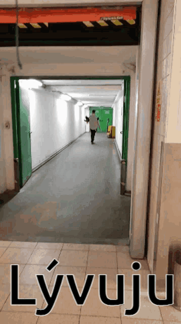 a man is walking down a hallway with the word lyvuju on the bottom