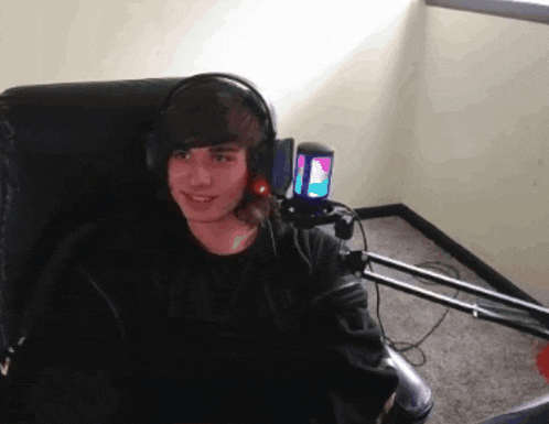 a young man wearing headphones sits in a chair in front of a microphone