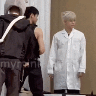 a man in a white lab coat is standing next to another man in a black jacket .