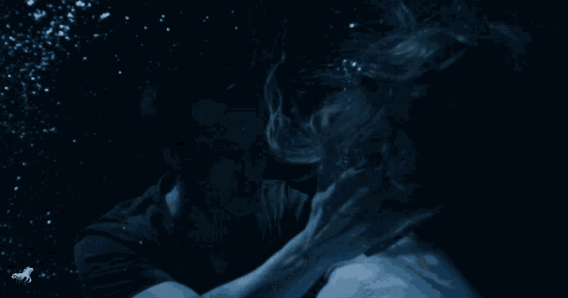a man and a woman are underwater with bubbles in the background