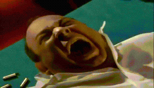 a man is laying on a table with his mouth open and bullets on the table .
