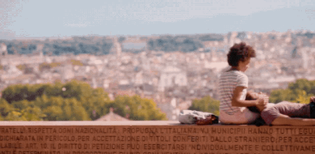 a woman laying on a man 's lap with a city in the background