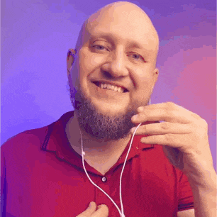 a bald man with a beard is smiling while wearing earbuds .