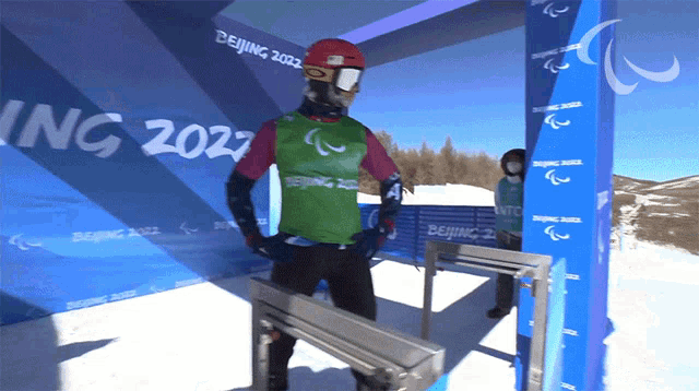 a person wearing a green vest that says beijing 2022 on it
