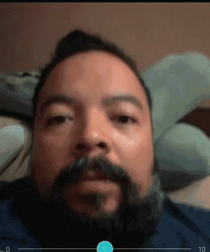 a man with a beard and mustache is laying on a bed with the number 5 on the bottom right
