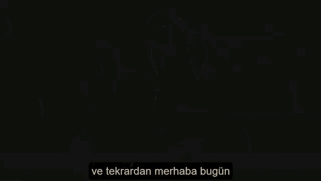 a man in a tuxedo is playing a guitar in a dark room with a caption that says ve tekrardan merhaba bugun