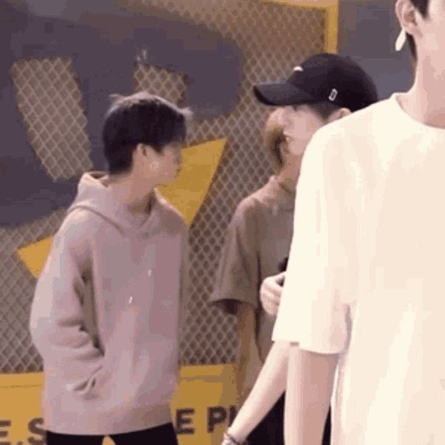 a group of young men are standing next to each other in front of a yellow sign .