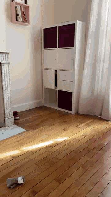 a white shelf with purple bins sits in a room