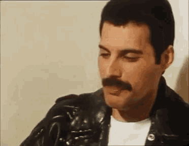 a close up of a man with a mustache wearing a black leather jacket .