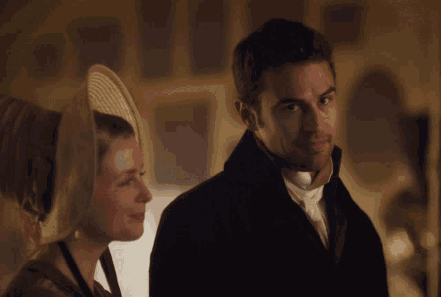 a man and a woman are looking at each other in a dark room