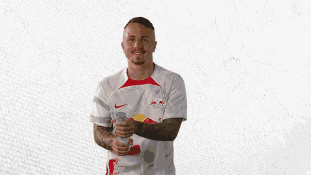 a man in a red bull shirt holds a can