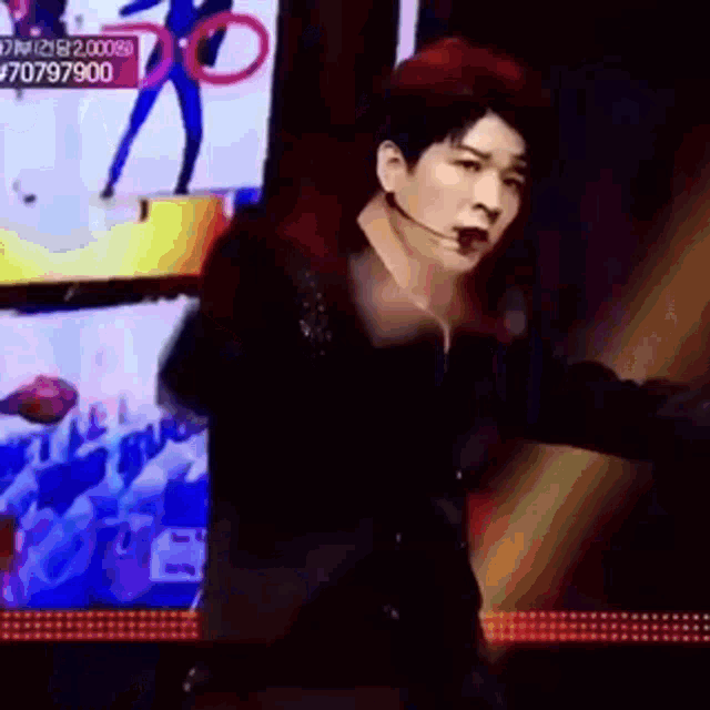 a man wearing a microphone is dancing in front of a screen that says ' 70707900 ' on it
