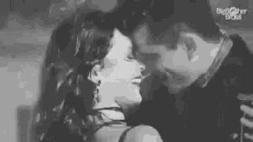a man and a woman are kissing each other in a black and white photo .