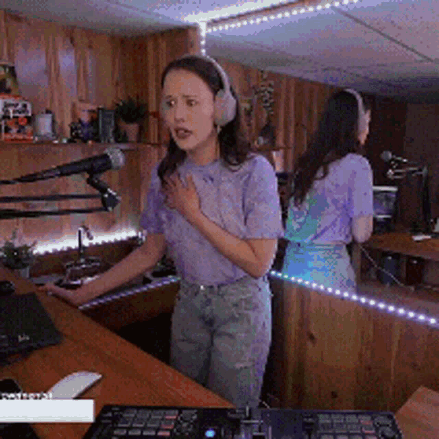 a woman wearing headphones is singing into a microphone in front of a mirror