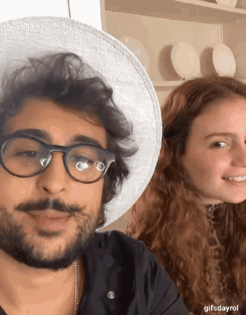 a man with glasses and a beard stands next to a woman
