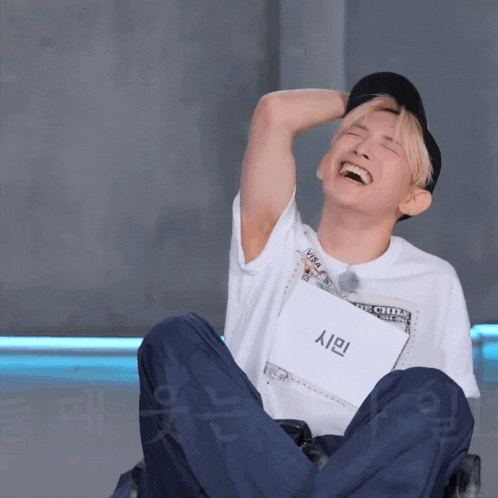 a man is laughing while holding a piece of paper that says ' s / i ' on it