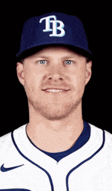 a man wearing a blue tb hat and a white jersey