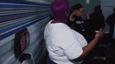a woman with purple hair is wearing a white shirt that says zeusq