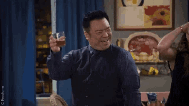 a man in a suit and tie is drinking from a glass .
